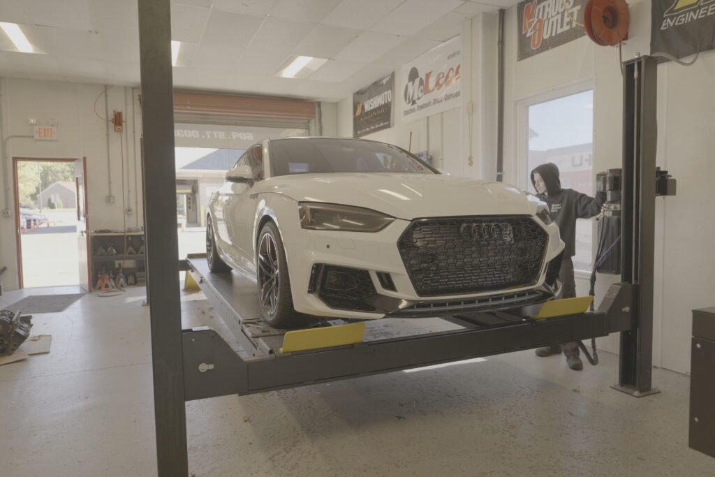 White car on lift being prepped for alignment