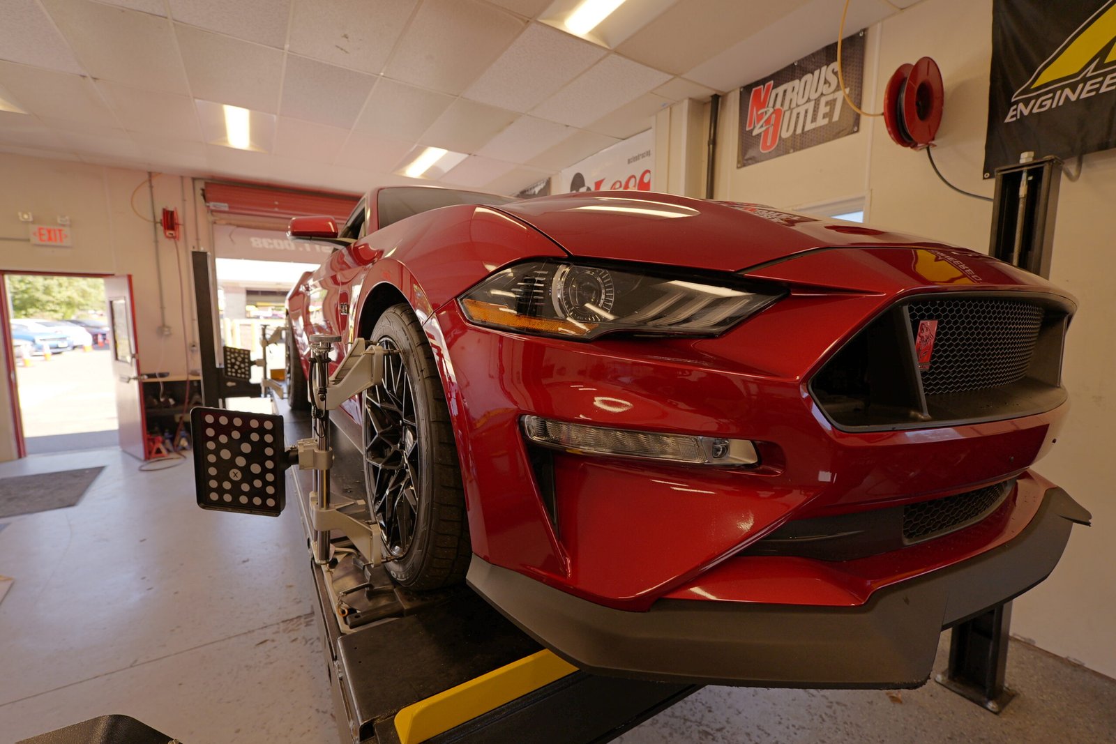 red car on lift with alignment markers on wheels